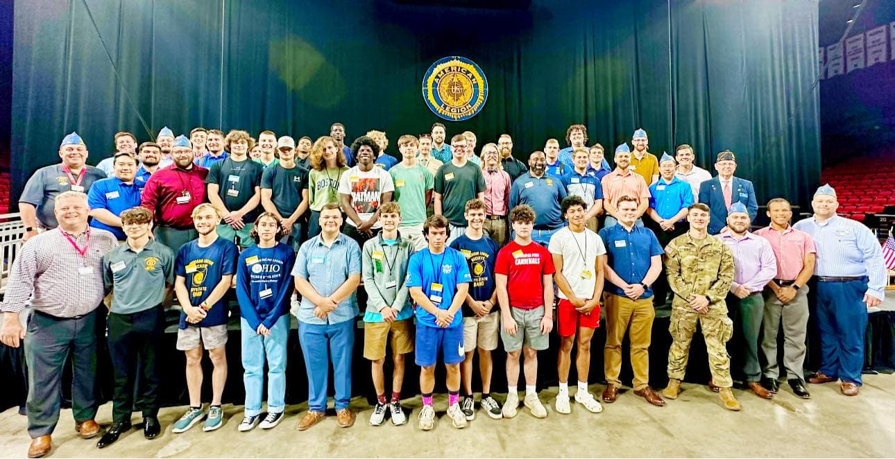 Group of dozens men and boys smiling standing on stage at Miami University